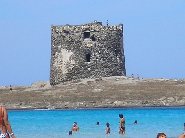 Dalla spiaggia di stintino, si vede oltre il mare blu' l'isolotto che ospita la torre di avvistamento.